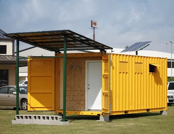 Rapid Deployment: Containers for Disaster Relief and Emergency Shelters Yellow modified shipping container with a covered porch and solar panel, used as an emergency shelter or field clinic.