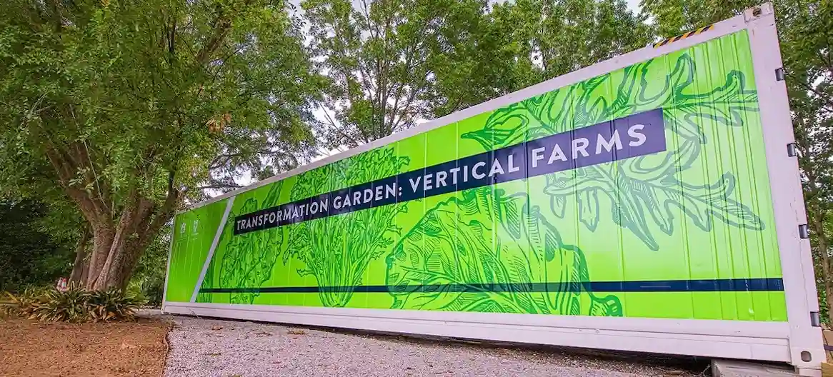 The Future of Food: Shipping Containers for Vertical and Hydroponic Farms Long white shipping container brightly branded with "VERTICAL FARMS" graphic, used for high-tech agriculture.