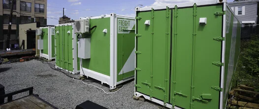 Scalable Farming: Container Farms for Hydroponics and Controlled Growing A row of green and white shipping containers with visible AC units, set up as a modular commercial vertical farm operation.