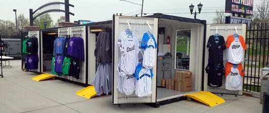 The Pop-Up Solution: Event Retail, Merchandise Kiosks, and Temporary Shops Two white shipping containers opened to create a retail shop, displaying merchandise racks at an event or outdoor venue.