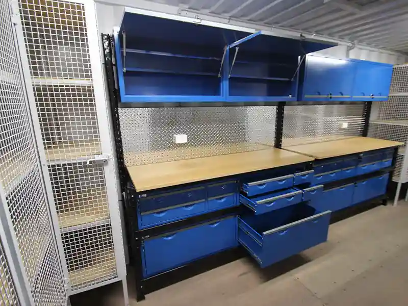 Interior de taller de contenedor profesional con cajones azules, banco de trabajo de madera, placa de fondo de diamante y taquilla de malla segura.