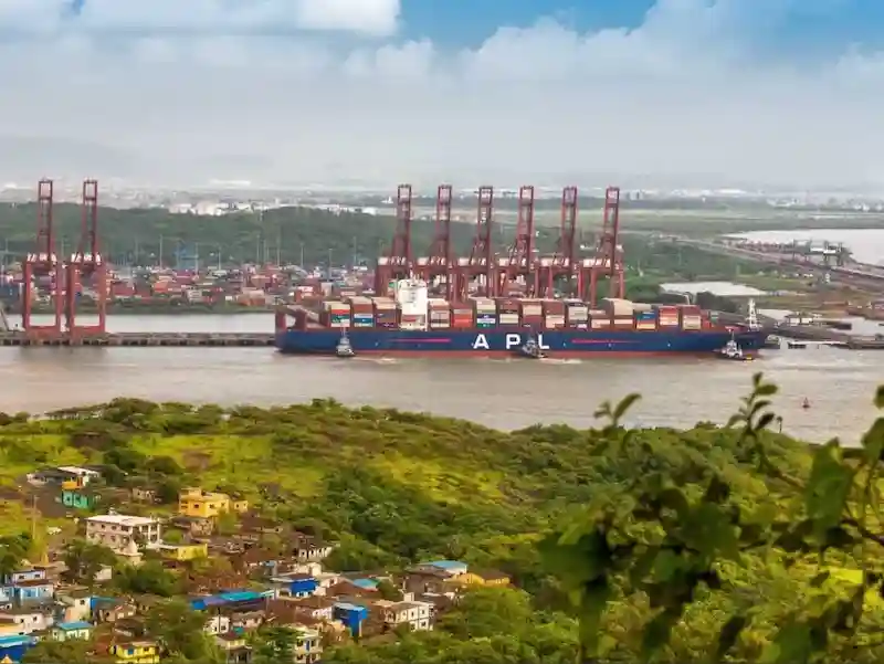 Un portacontenedores azul de APL navegando junto a las grúas rojas de la terminal GTI.