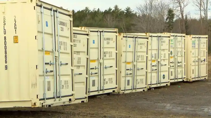 Fila de contenedores de transporte de 20 pies, limpios y de color beige, con las especificaciones de las puertas a la vista, que simbolizan un inventario nuevo y de alta calidad.