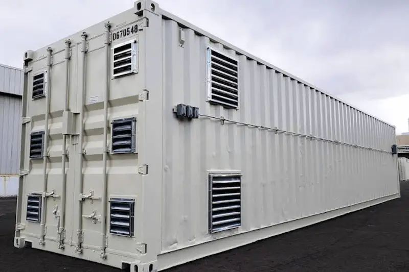 Long beige ventilated shipping container showing multiple installed louvered vents along the side panel for air circulation.