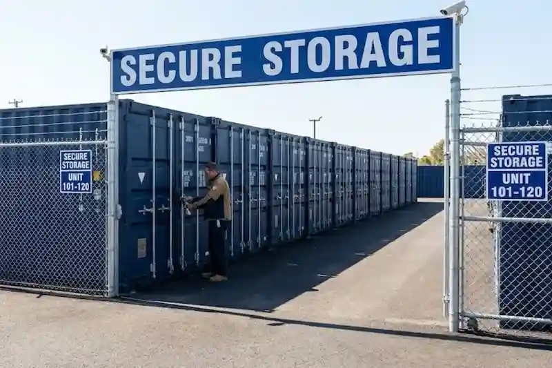 A worker locking a blue storage container in a secure yard with "Secure Storage" signage.