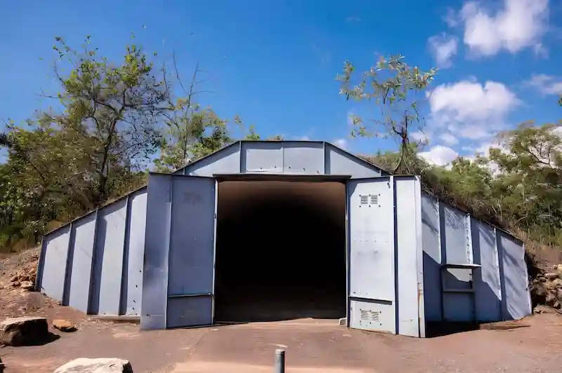 Large, dome-shaped underground bunker entrance built into a hillside with large steel doors, representing secure shelter.