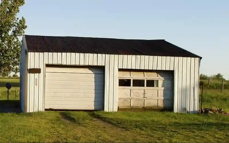 Old, weathered, two-bay traditional metal garage with a corrugated roof, illustrating a need for modern storage.