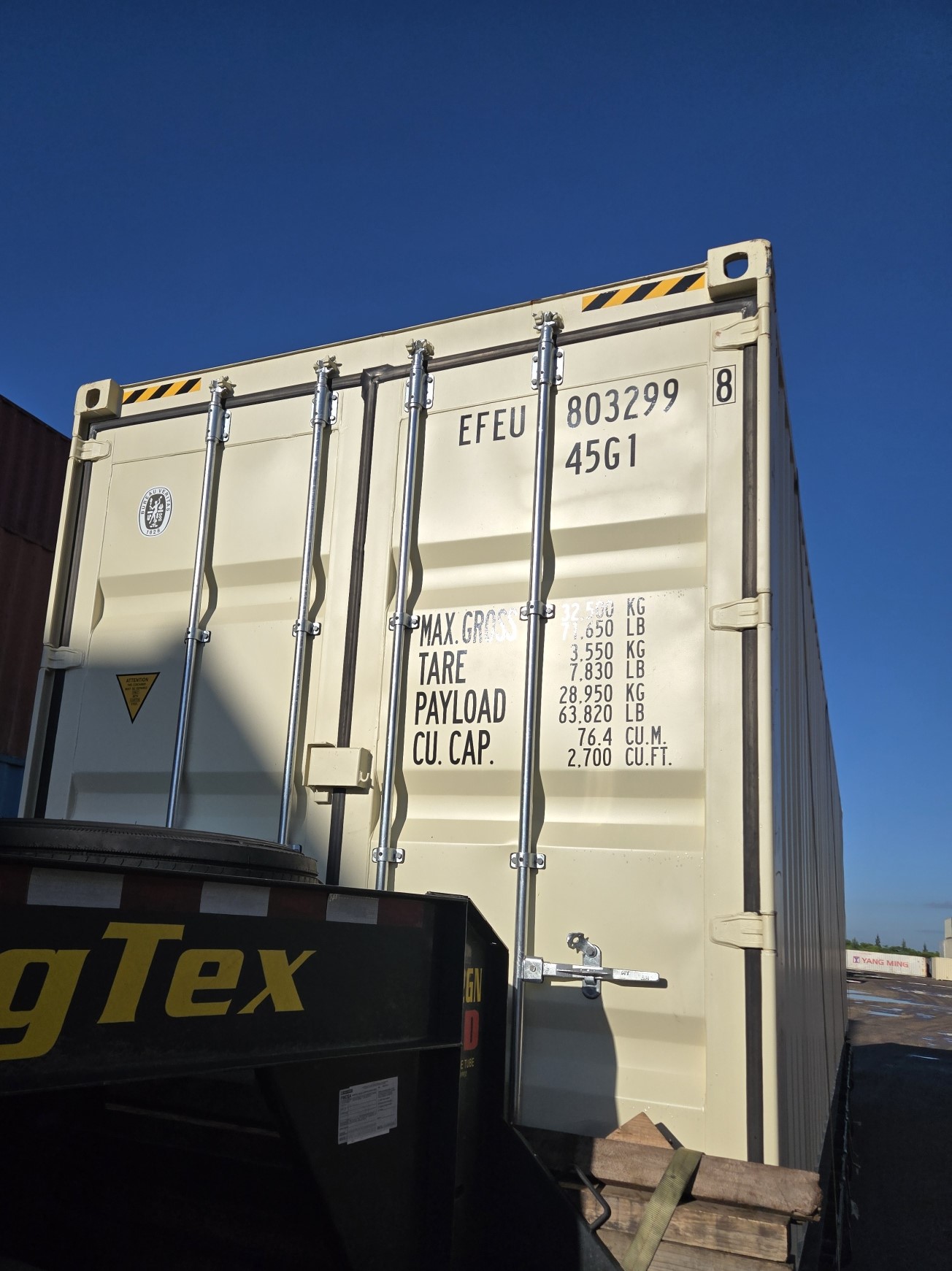 Rear doors of a 40ft high cube new shipping container on a tilt-bed trailer with door hardware visible