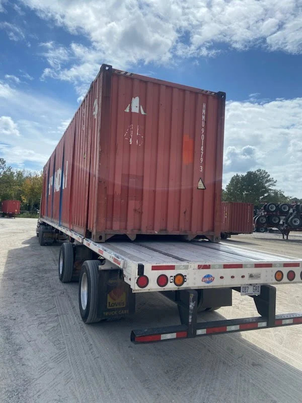 Rear view of a red 45ft high cube shipping container on a flatbed chassis trailer