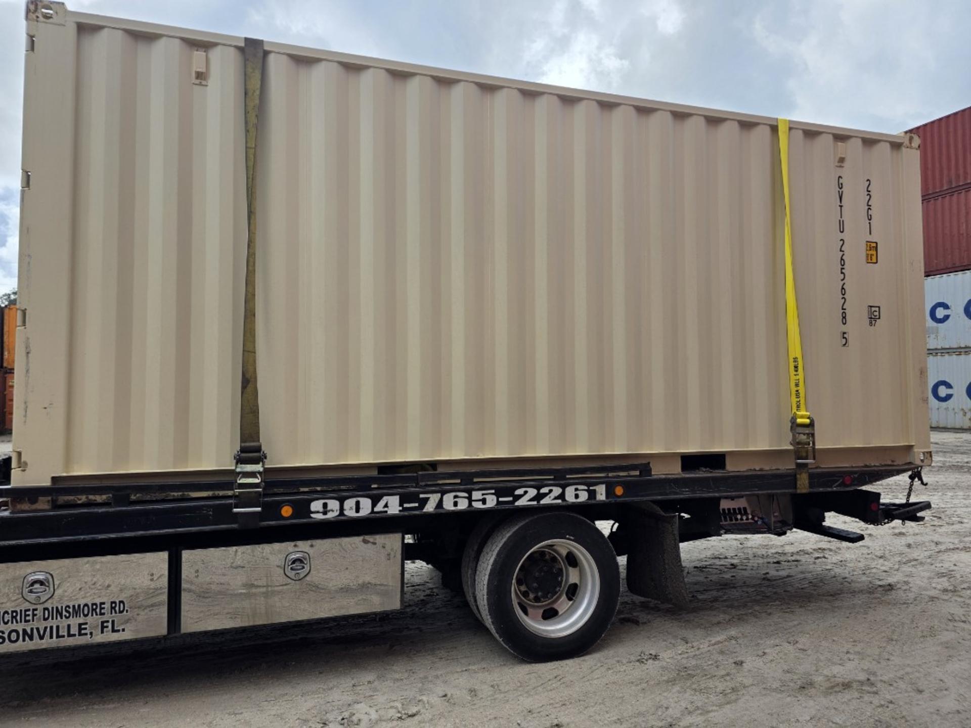 Side view of a beige 20ft container secured with yellow straps on a black flatbed truck.