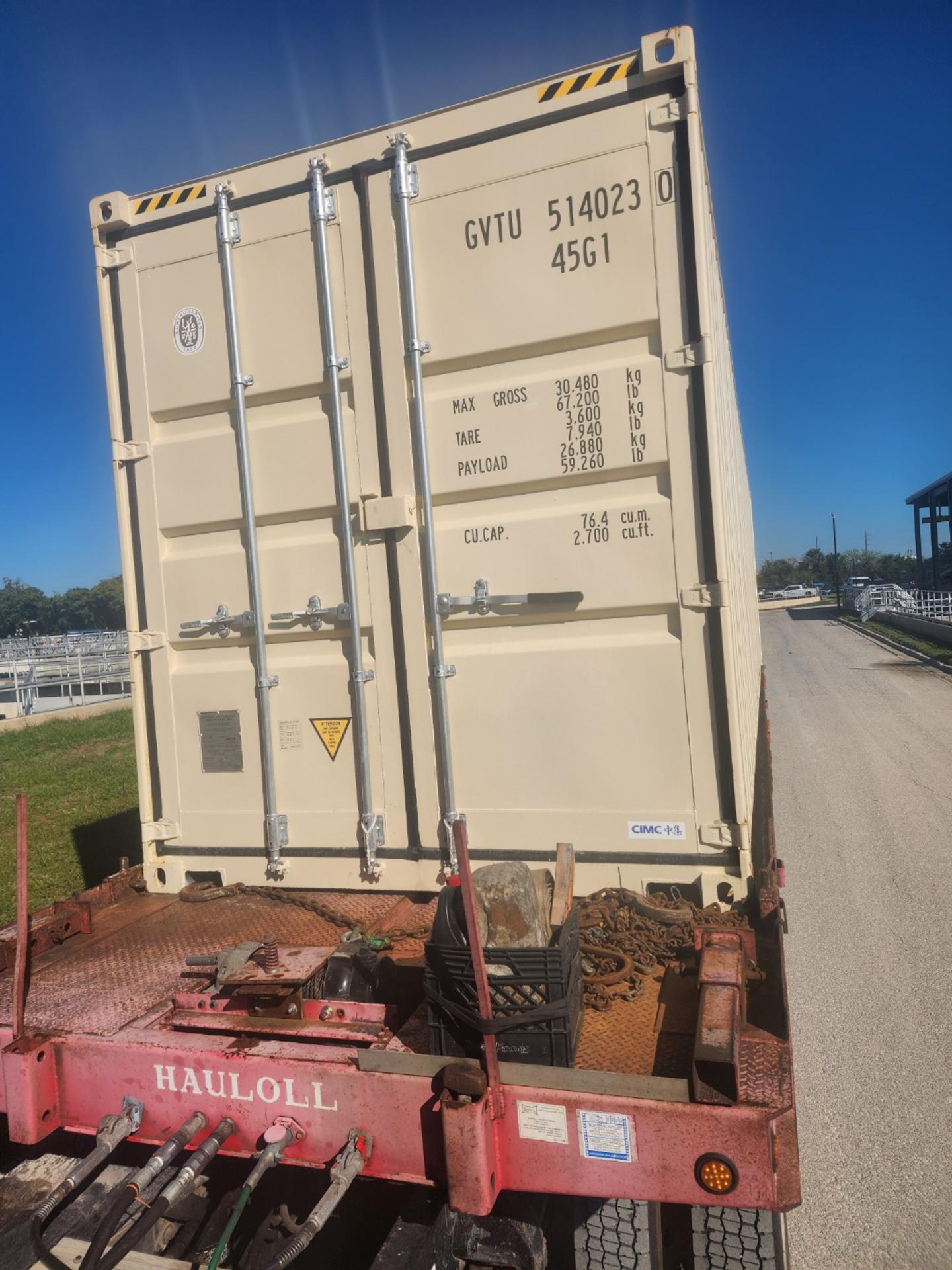 Side wall of a beige 40ft high cube container positioned at ground level near a fenced site