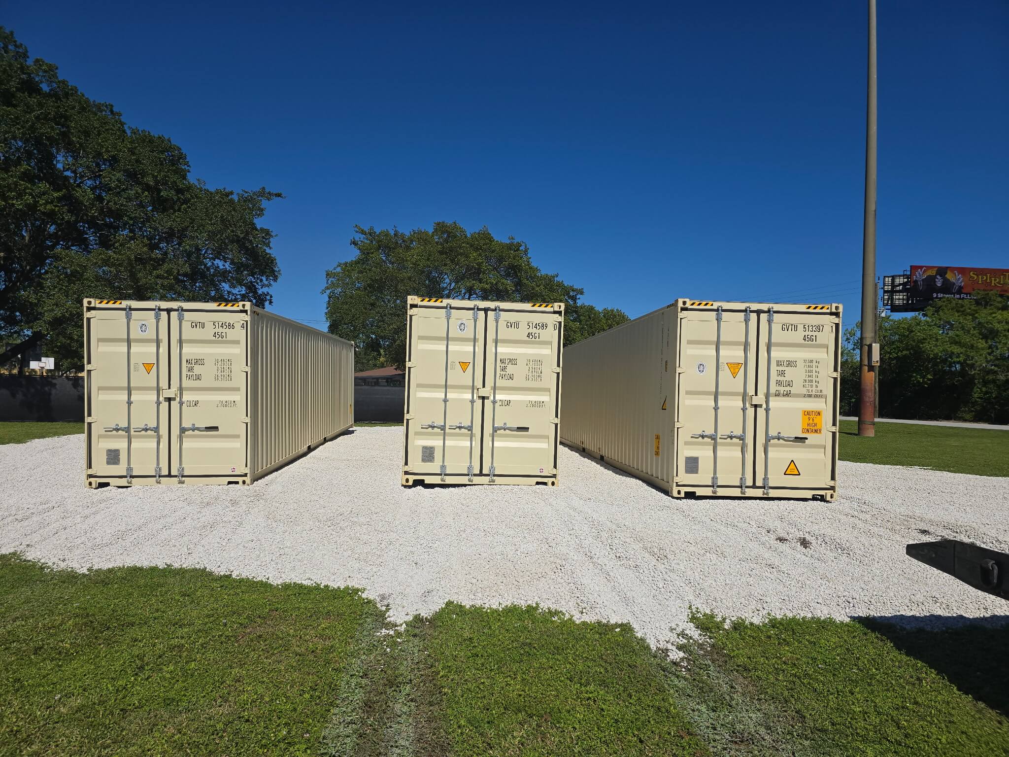 Three 40ft high cube shipping containers positioned side by side on a prepared gravel pad